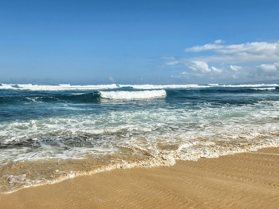 Waves rolling onto a sandy beach on Oahu
